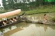 A naked woman sitting on a log next to a boat.