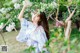 A woman in a blue kimono standing in front of a tree.