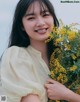 A woman holding a bunch of yellow flowers.