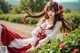 A woman in a red and white dress sitting in a field of roses.