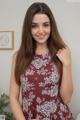 A woman in a red and white floral dress posing for a picture.
