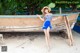 A woman in a blue dress and hat standing next to a boat.