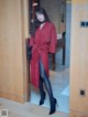 A woman in a red coat and black tights standing in a doorway.