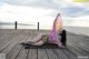 A woman laying on a wooden boardwalk with a scarf over her head.