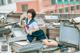 A woman in a school uniform sitting on top of a pile of books.