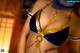 A woman in a blue and gold bikini with a chain around her neck.