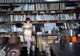 A woman standing in front of a book shelf holding a book.